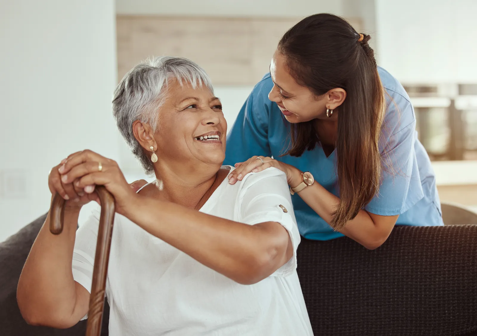 Carer and resident sharing a laugh in a bright conservatory