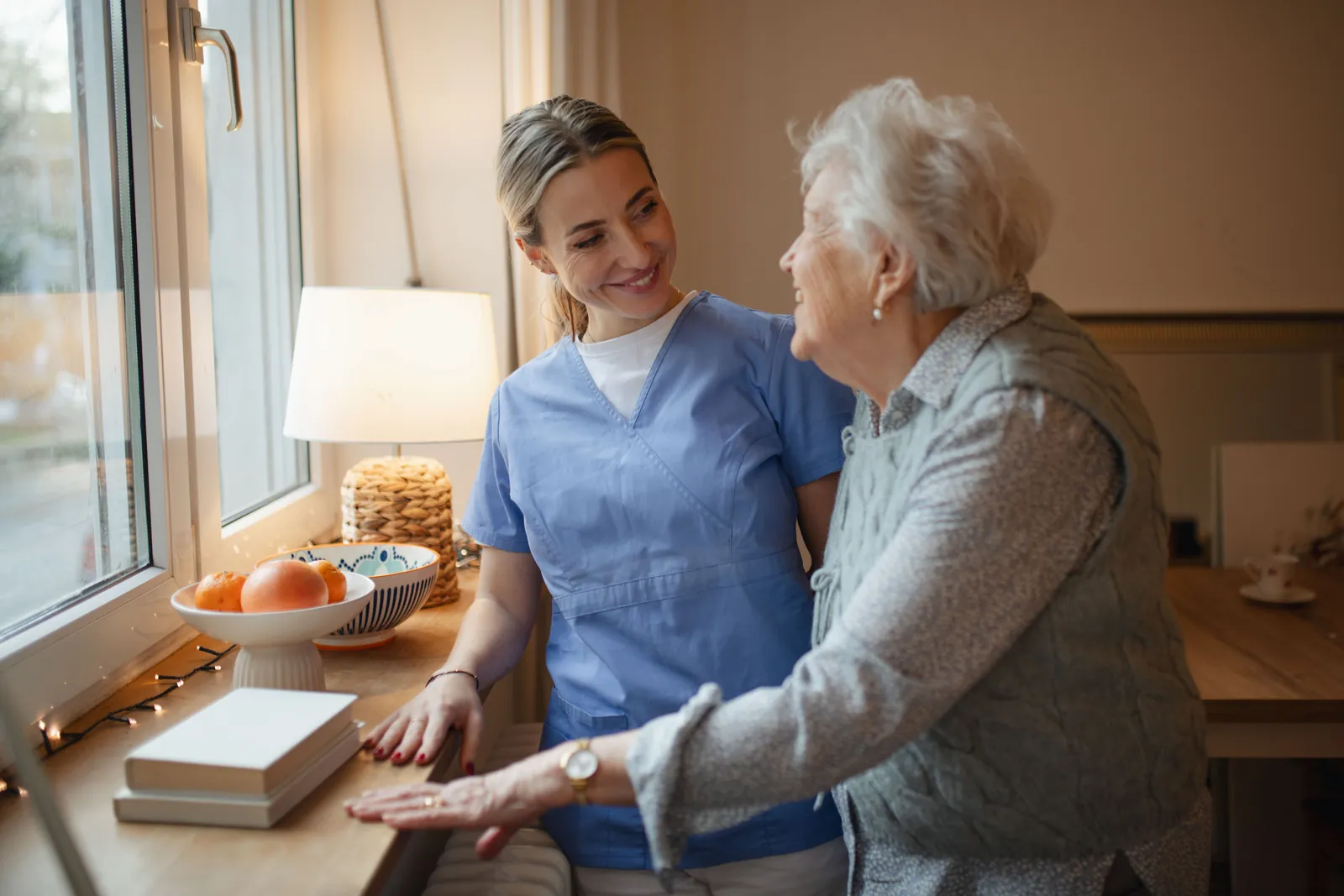 Carer and older woman talking together by the window